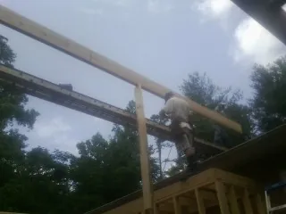 Carpenter setting a ridge beam over a new addition frame — Ice Dam Removal by Roofing Brothers in Big Arm