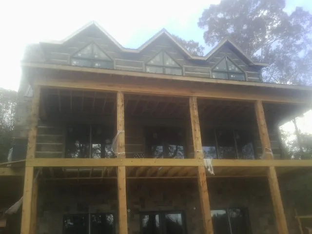 Dormers and porch framing on a large log home under construction — Roof Coating work by our crew in Big Arm