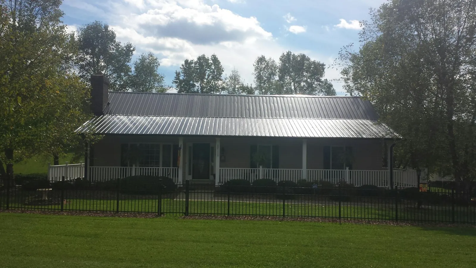 Gray metal roof on a brick ranch with a full width front porch — Gutter Guard Installation work by our crew in Big Arm