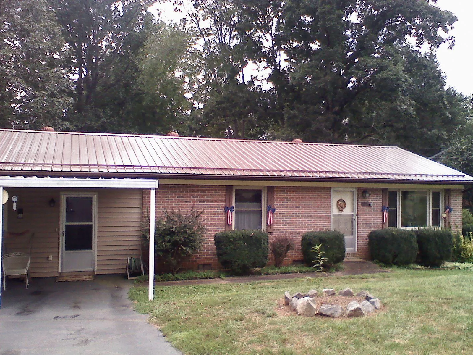 Bronze metal roof and carport on a brick ranch home — Roof Repair work by our crew in Big Arm